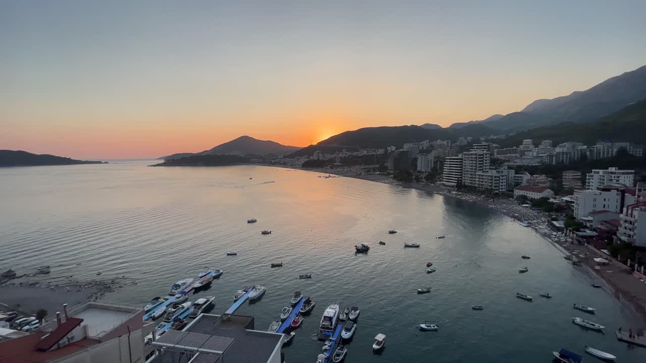 Splendido tramonto su Rafailovići in Montenegro, ripresa aerea con drone al tramonto in una giornata di sole, il sole che tramonta sulla montagna con barche e auto in vista