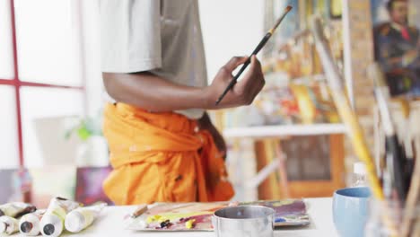 Midsection-of-african-american-male-painter-painting-on-canvas-in-artist-studio