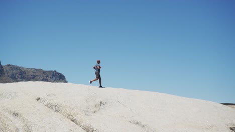 senior african american man exercising running on rocks by the sea