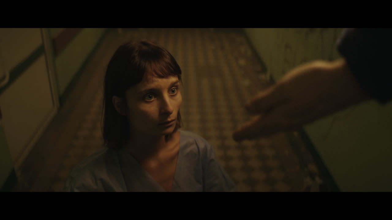 A girl and strange clown on stilts in a dark corridor at night