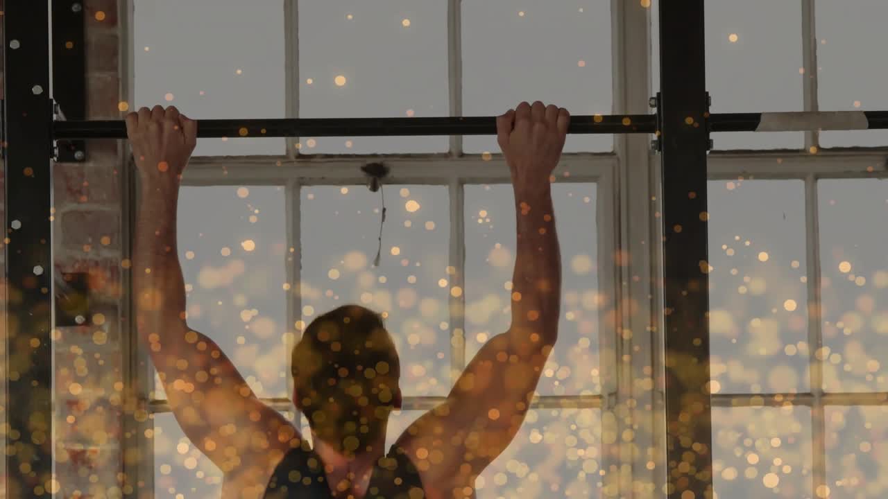Homem segurando a barra de elevações e fazendo pull-ups para força na academia, com partículas douradas cobrindo a parte inferior do tronco.