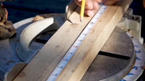 close up of carpenters hand pencilling marking on circular metal measuring board