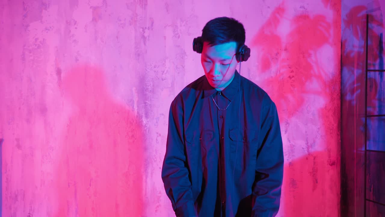 un dj moderno de apariencia asiática interpreta una pista de música con luces de neón.