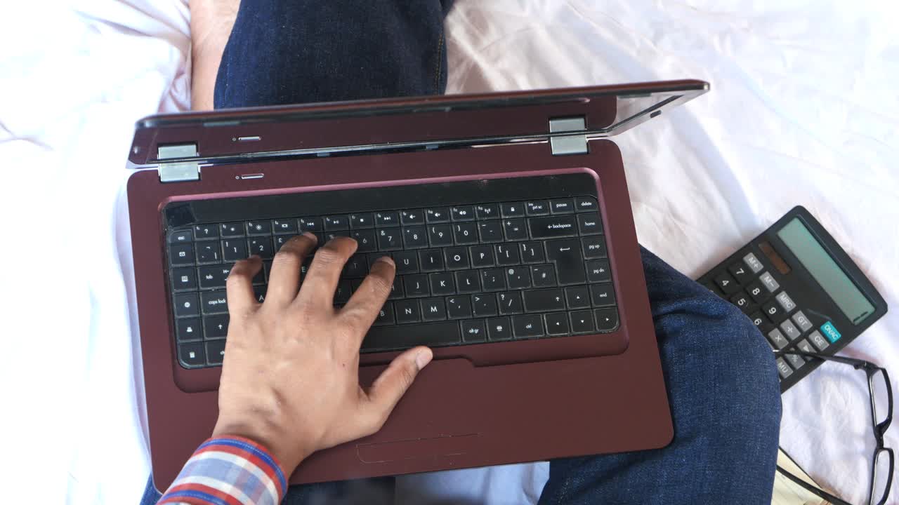 침대에 노트북으로 일하는 사람