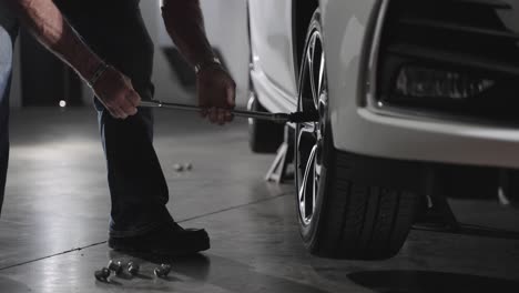 mecánico irreconocible quitando tuercas de la rueda del coche con llave de tuercas, cámara lenta