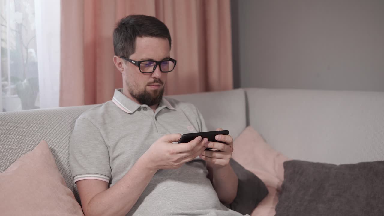 소파에서 스마트폰을 사용하는 남자