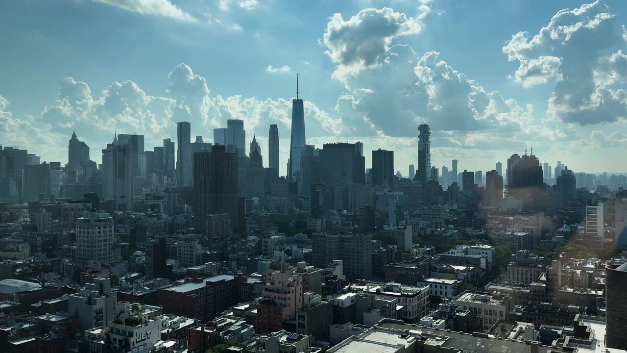 Ampia vista dei grattacieli di Manhattan sotto un cielo pomeridiano luminoso con nuvole sparse.