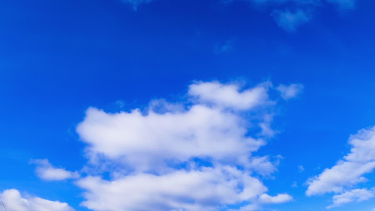 Azure sky with changing cumulus clouds. Horizon clears up and clouds float away. Low angle view.