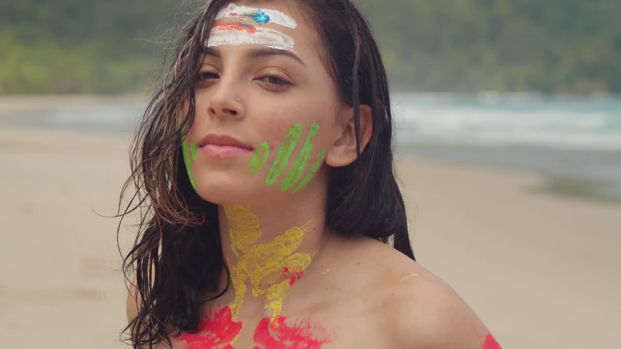 A girl, bikini-clad and covered in body paint, basks in the sun on a Caribbean beach