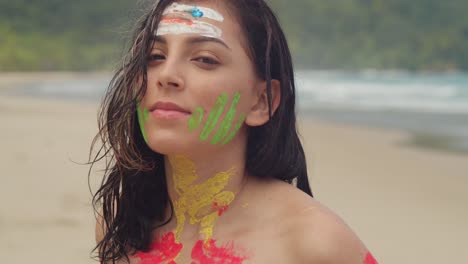 a girl, bikini-clad and covered in body paint, basks in the sun on a caribbean beach