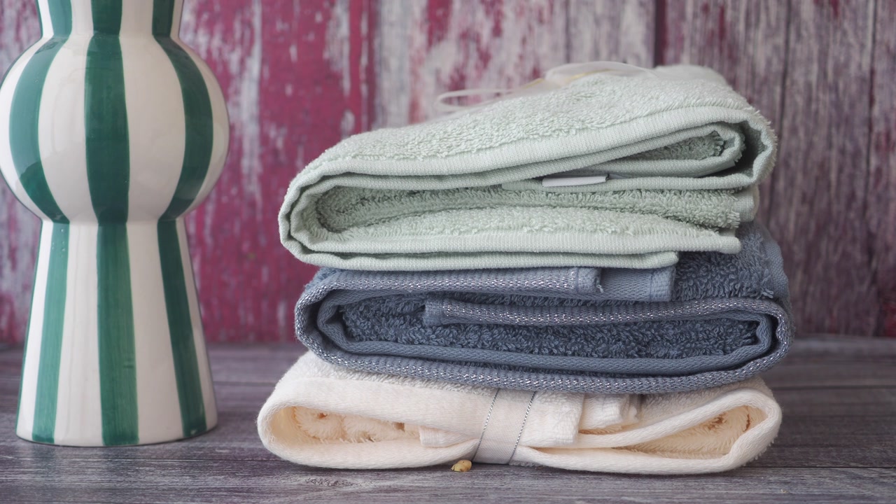 Stack of Soft Folded Towels in Pastel Colors on Wooden Background