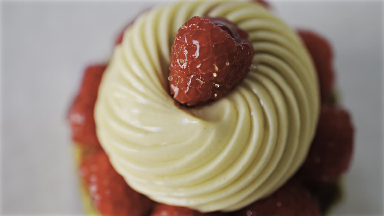 Close up of a pistachio raspberry tartlet on a white plate