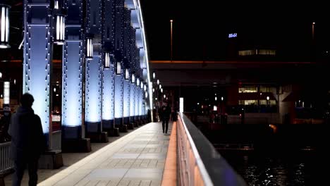 person walking on a brightly lit bridge at night