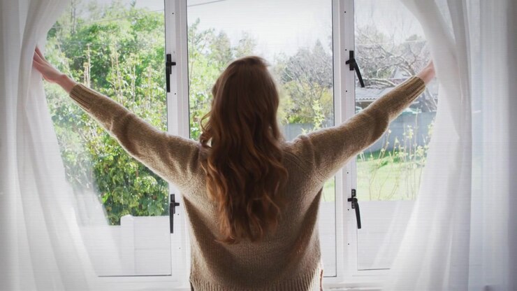 Glitch overlays appearing, woman standing backlit, pulling sheer curtains open, revealing garden