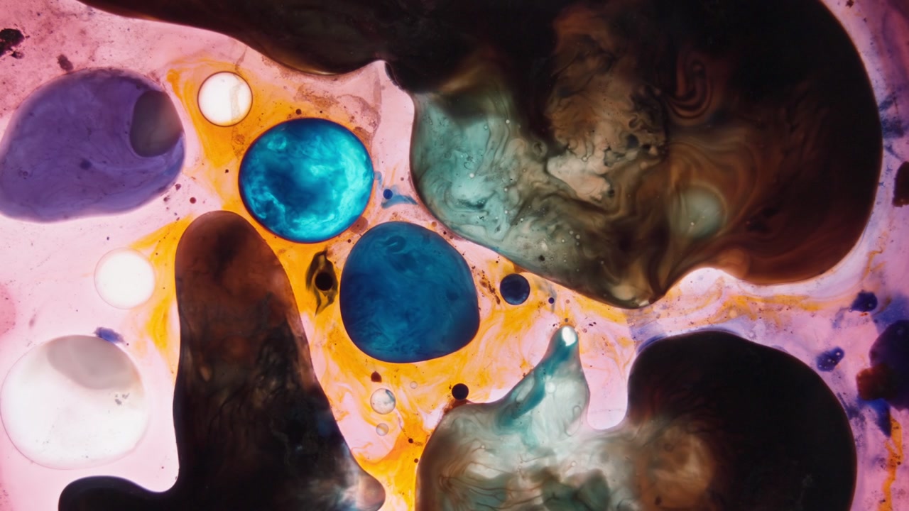 Goccioline di inchiostro blu e nero vibranti che si espandono in un ambiente fluido arancione. Primo piano che mostra movimenti organici e texture cellulari, ideale per progetti scientifici e sull'evoluzione.