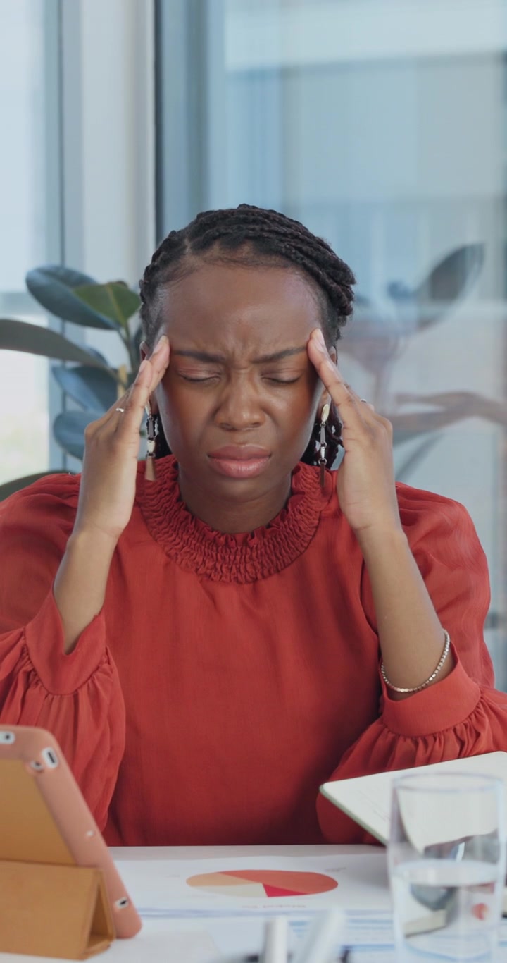 Stressed Businesswoman Rubbing Temples at Her Desk in Office