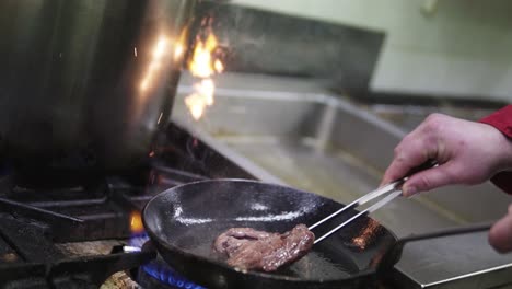 cocinar filete medio raro en una sartén en la cocina con llamas | camara lenta