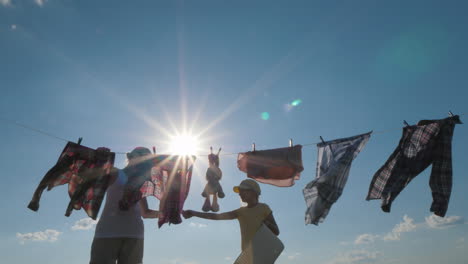daughter helps mom hang clothes for drying