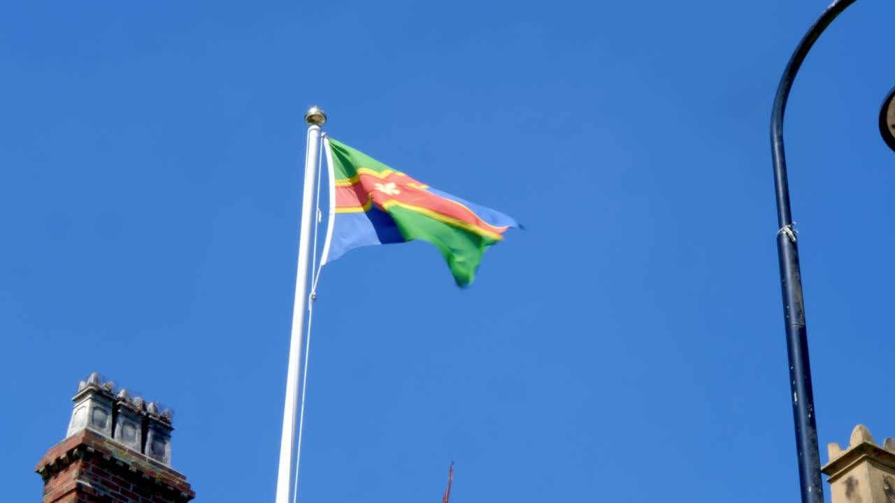 A colorful flag waving in the wind against a clear blue sky