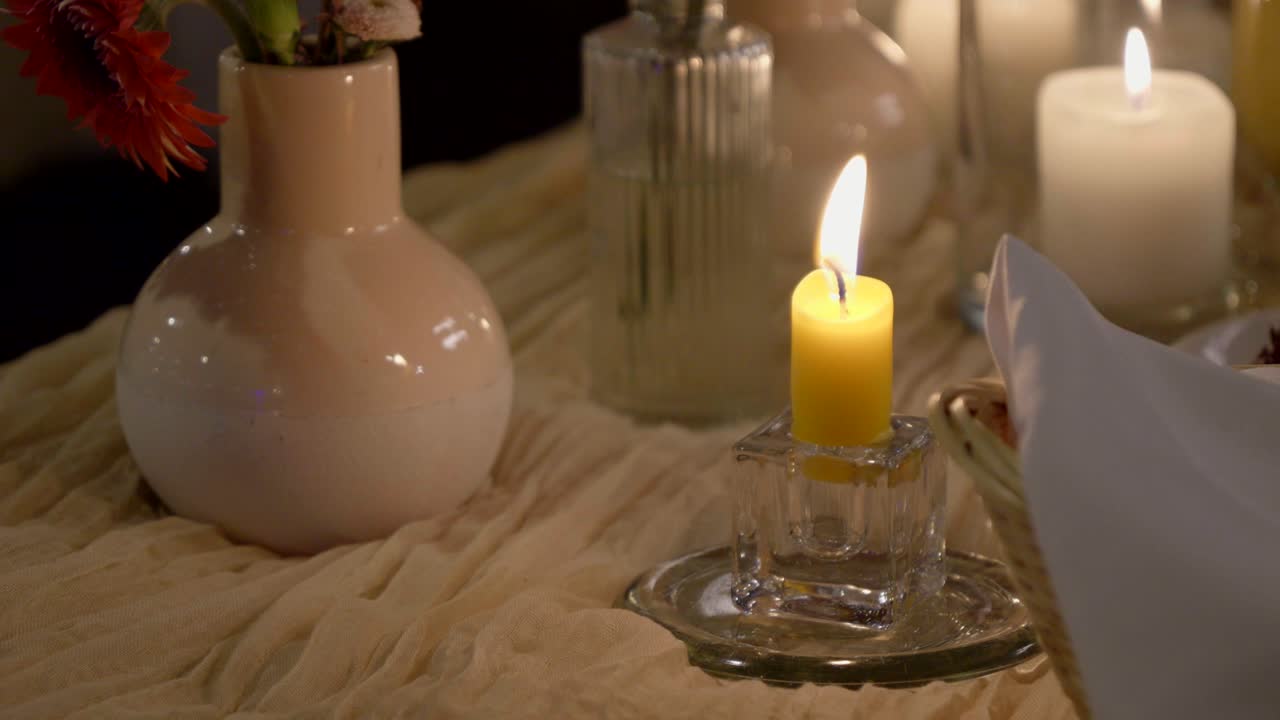 Bougie de cire jaune sur une table de mariage bohème avec des guirlandes lumineuses douces