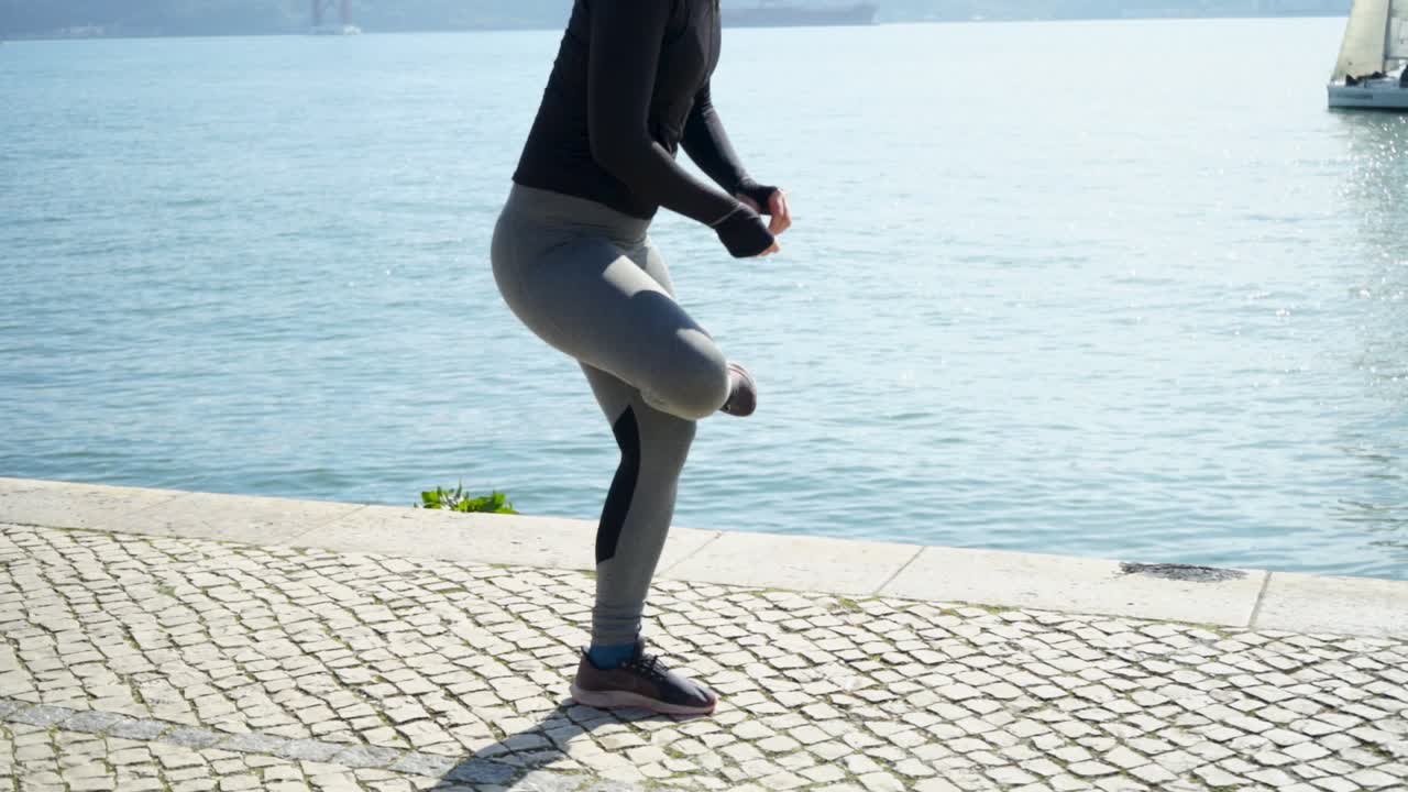 Sporty young woman exercising on embankment near river