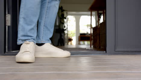 walking indoors, person in white sneakers and blue jeans entering home