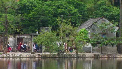 Las-Niñas-Andan-En-Bicicleta-Junto-A-Un-Lago-En-Vietnam