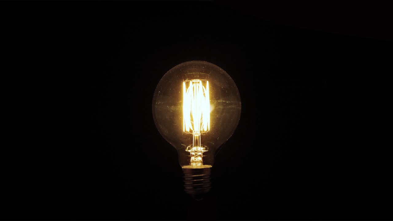 una bombilla de tungsteno parpadeando sobre un fondo negro.