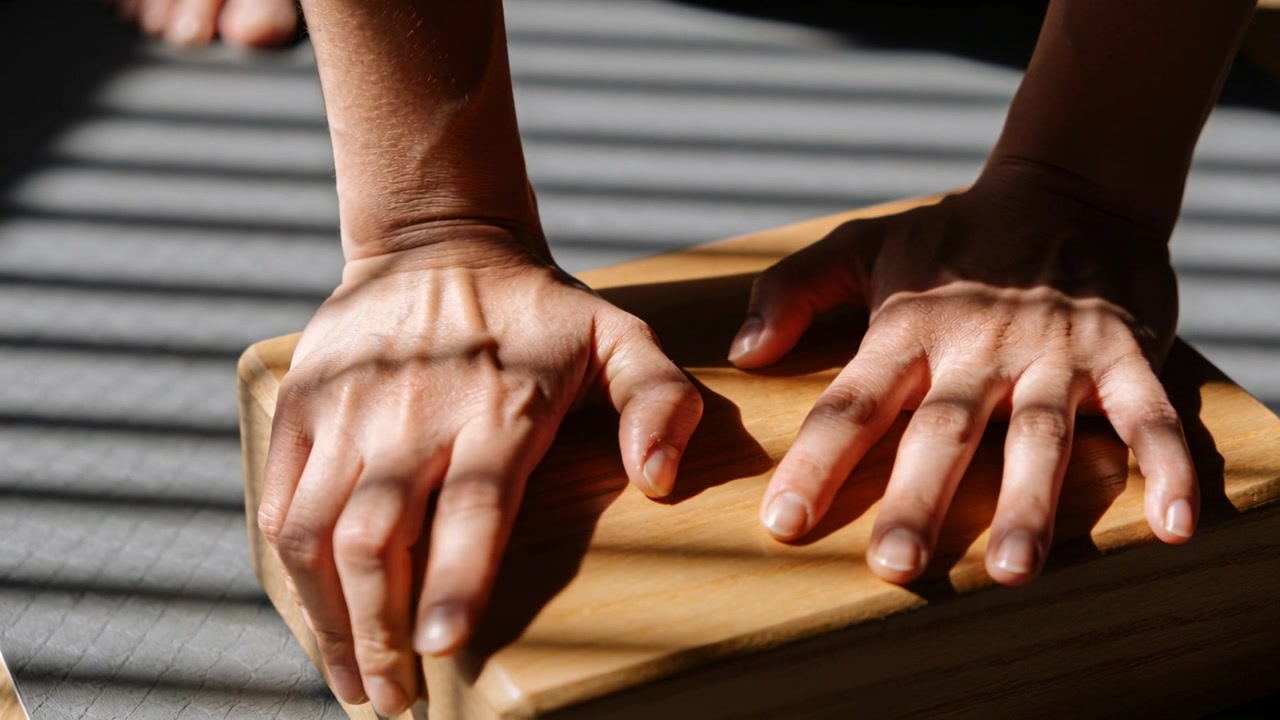Pressing person's bare hands, adjusting on touch on mat by window, with wooden block blind shadows