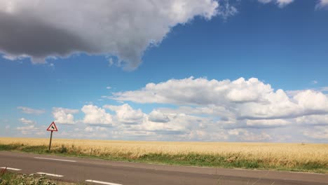 cloudy blue sky over highway and agricultural field - timelapse