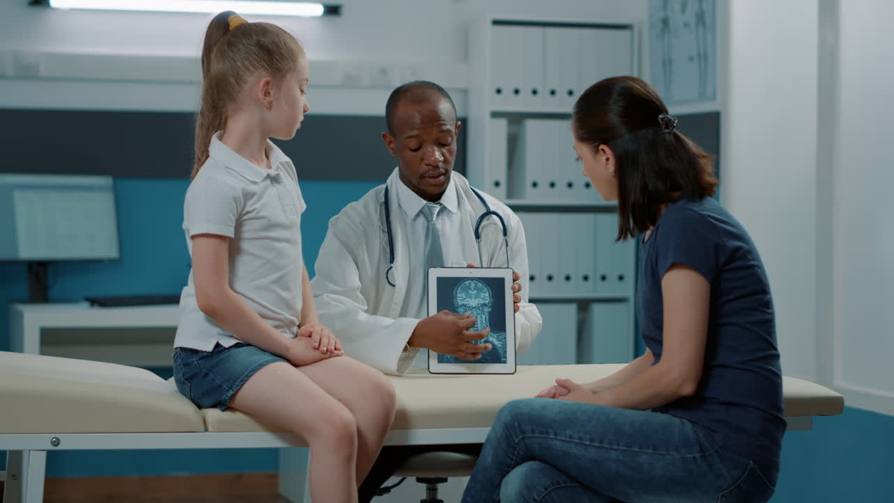 Medico che spiega i risultati dei raggi X a un bambino e sua madre