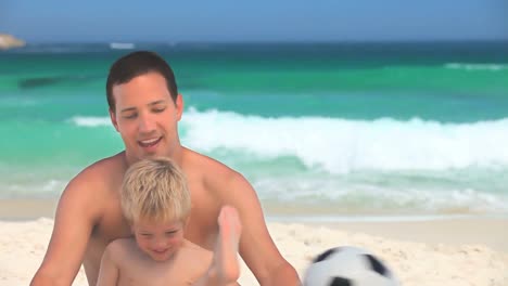 Padre-E-Hijo-Jugando-Con-Una-Pelota-De-Fútbol-En-La-Arena