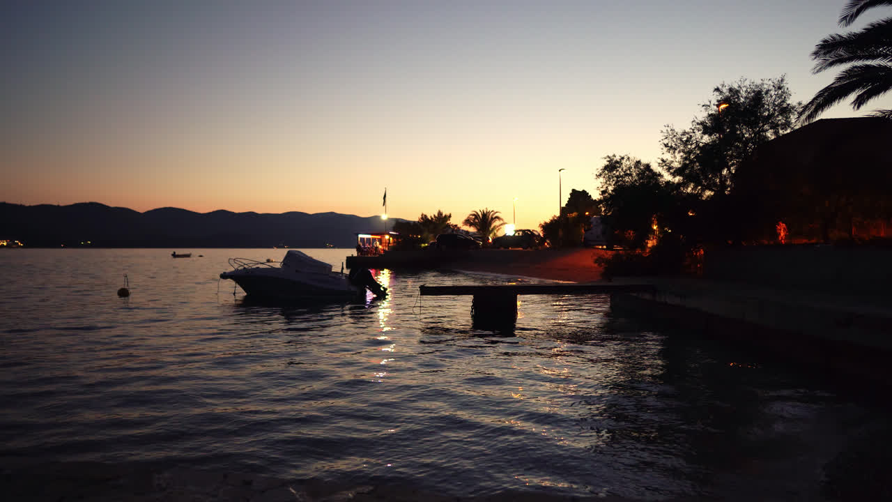 revelación de inclinación hacia arriba de un lago tranquilo con un barco atracado en el muelle en una puesta de sol