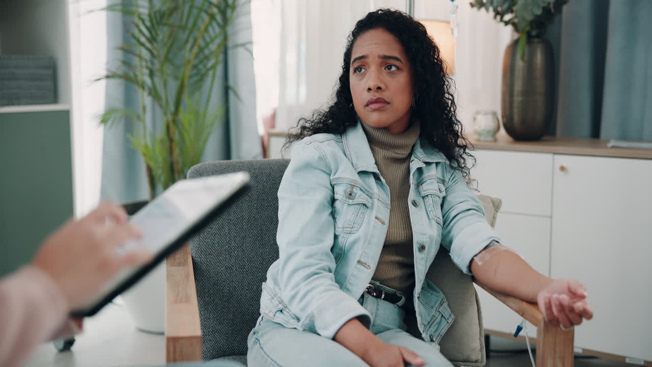 Woman sitting in a chair with an IV drip in her arm, talking to a doctor