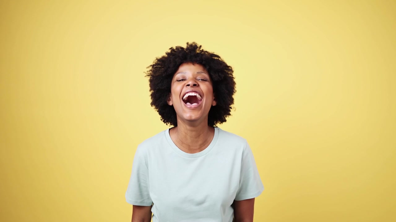 Happy Young Black Woman Laughing Heartily on Yellow Background