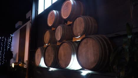 barriles de vino apilados a través de una pared de madera en una bodega