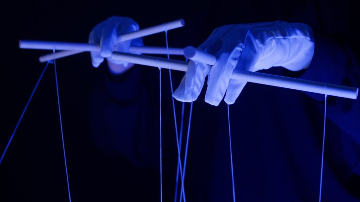 Gloved Hands Operating a Marionette Puppet Control Bar in Blue Light