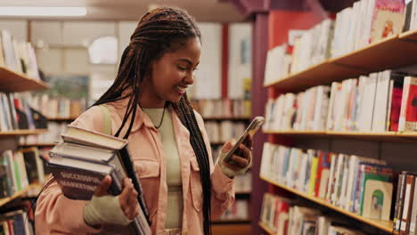 woman using phone while holding books in library