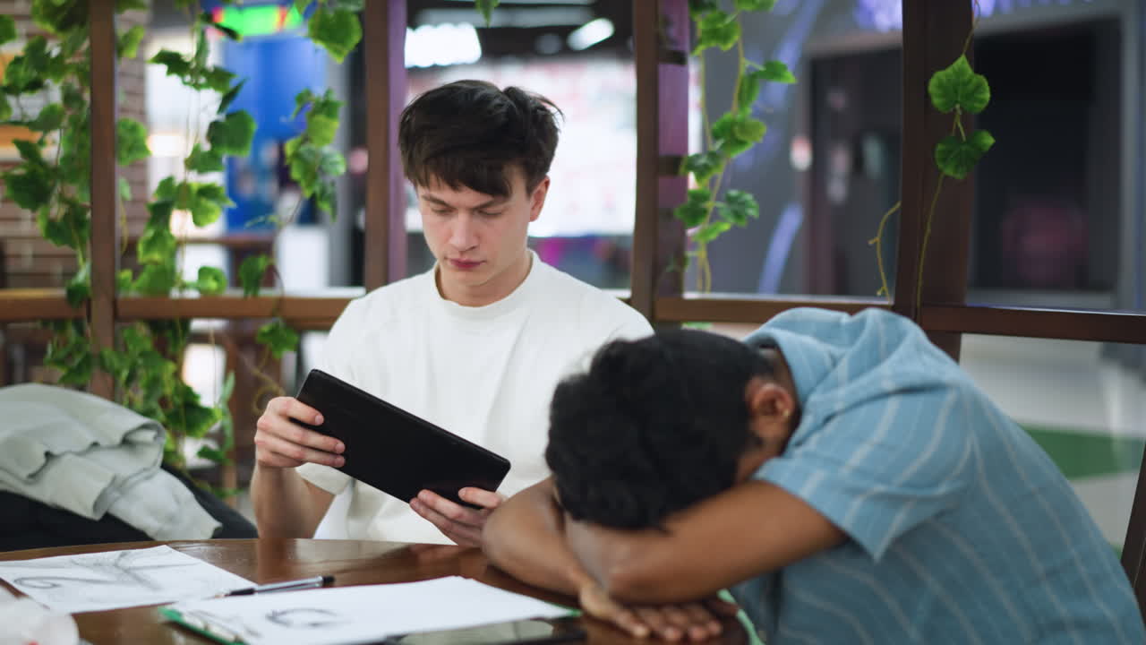 Close shot captures European boy with sweater draped around neck pulling garment off shoulders while intently playing handheld game device indoors under soft lighting energetic mood focus gameplay