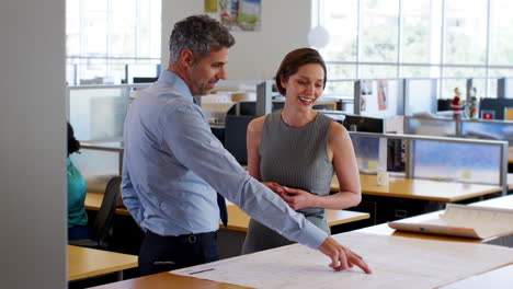 Female-and-male-colleagues-discuss-project-in-an-office