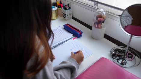 over-the-shoulder view of a girl writing in a notebook, 4k