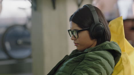 young hispanic woman student using digital laptop computer typing working online brainstorming sharing creative social media ideas listening to music wearing headphones in colorful trendy office