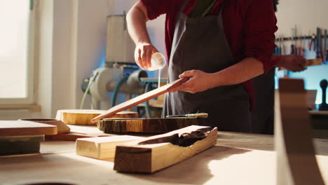 Cabinetmaker-in-assembly-shop-lacquering-wooden-board,-close-up