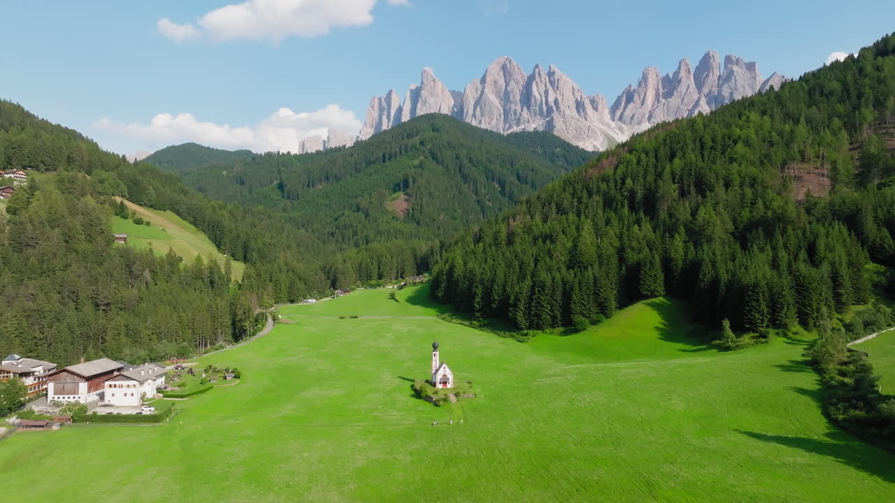 Aerial: The Odle group mountain peaks and the Church of St. John in Val di Funes, South Tyrol, Dolomites, Italy