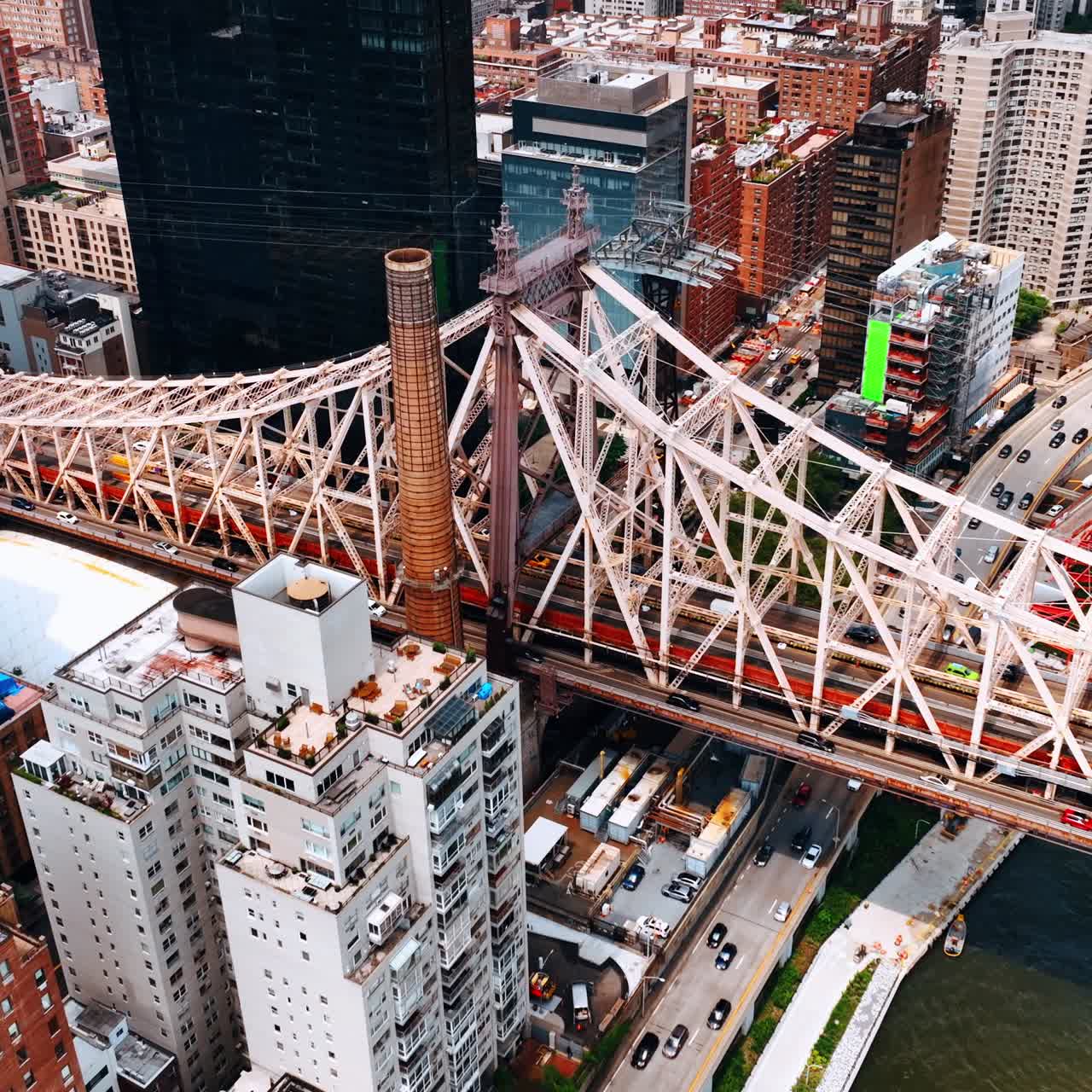 Waterfront part of the Queensboro Bridge from aerial view. Multiple cars move by the bridge and below it