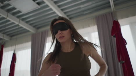 fitness coach blindfolded her eyes and punches air with focus and energy during solo movement practice in brightly lit wellness studio, exploring body awareness through sensory isolation