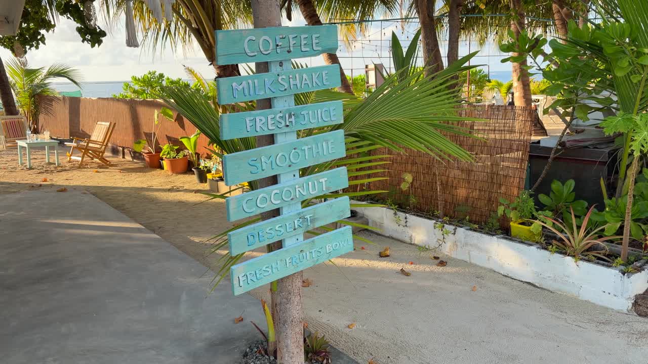 Cartello direzionale sull'isola di Maafushi, Maldive. Scena di un villaggio tropicale con caffè.