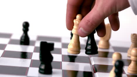 white chess piece knocking over a black one