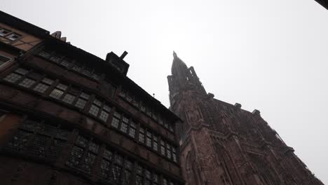 view onto the strasbourg cathedral against a cloudy sky backdrop, towers rise proudly, flanking the entrance and providing a glimpse of the splendor that lies within