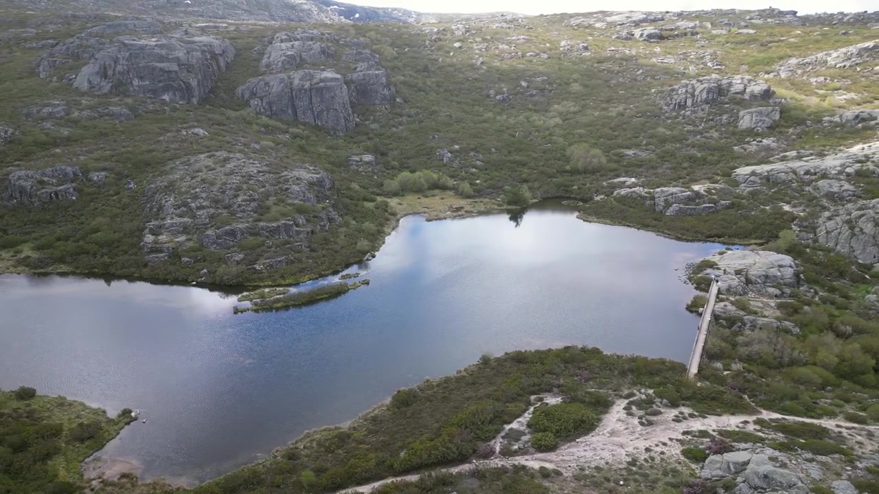 Luftoptagelser med drone af Serra da Estrela, Portugal: klippefyldte bjergtoppe, vandreservoirer og et stort naturlandskab under klart lys. Ideel til rejse- og naturprojekter